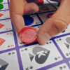 een persoon die een fiche neerlegd op het speelbord van het spel Sequence Classic
